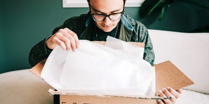 A man opening a cardboard box in his home.