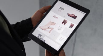 A person holding an iPad showing online store product prices