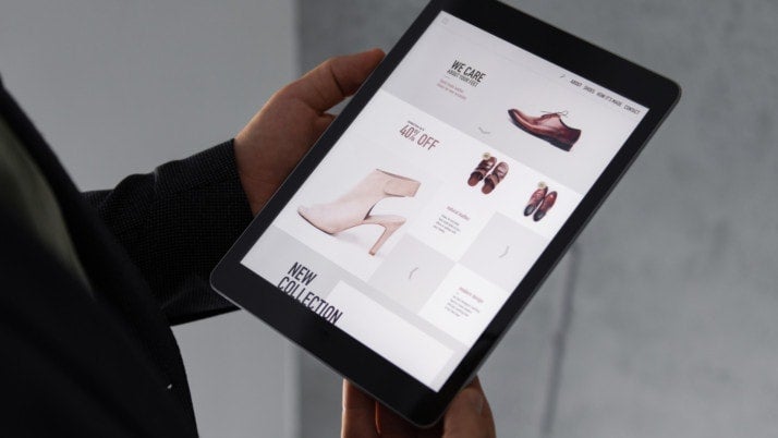 A person holding an iPad showing online store product prices