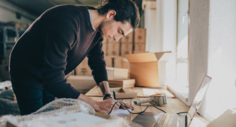 Man writing notes in the diary while standing at his workplace.