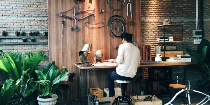 Ein junger Unternehmer sitzt an seinem Werktisch und tüftelt an seinem Produkt.