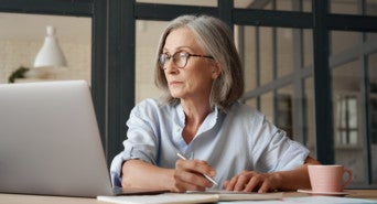 Frau an Laptop macht sich Notizen zur DSGVO für ihren Onlineshop