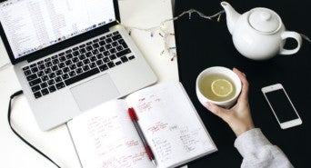 Symbolbild: Ein Schreibtisch mit Laptop und Kaffeekanne steht für Zuahusearbeit in Zeiten des Coronavirus