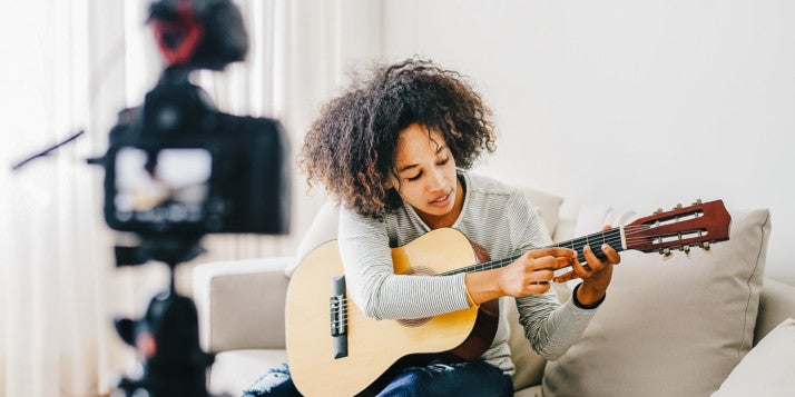 Eine junge Frau streamt eine Gitarrenstunde