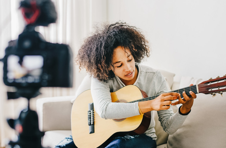 Eine junge Frau streamt eine Gitarrenstunde