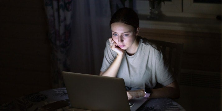 Eine Freelancerin brütet nachts vor ihrem Laptop und überlegt, wie sie einen Auftrag höflich ablehnen kann.