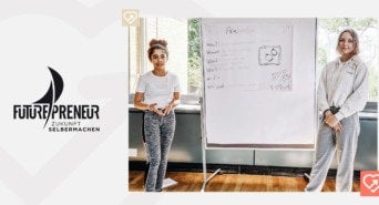 Zahraa und Neele stehen vor einer Tafel und präsentieren bei Futurpreneur ihre Idee
