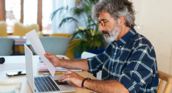 Ein Selbstständiger sitzt an seinem PC und arbeitet an seinen Mahnung-Vorlagen