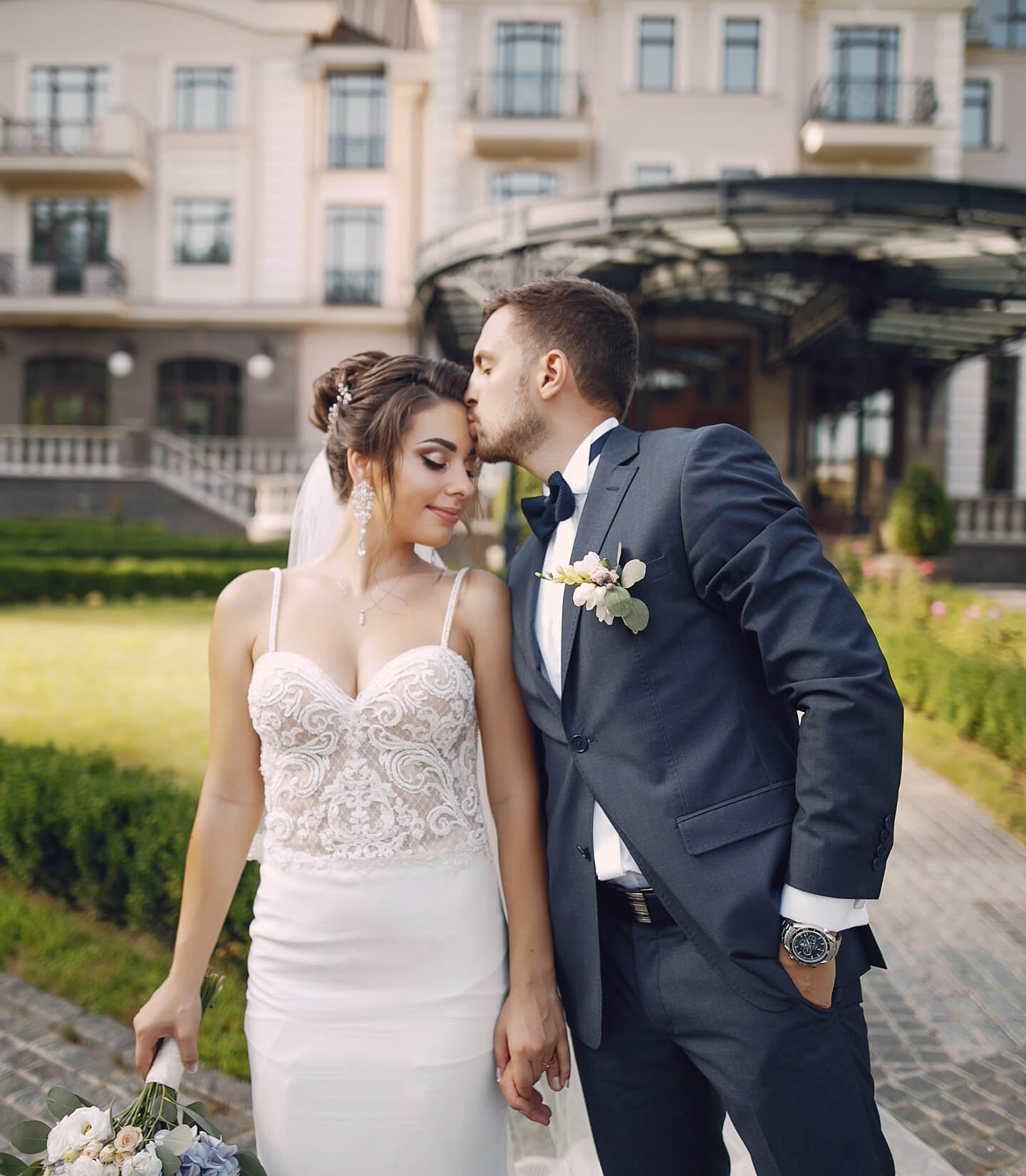 A married couple stand outside their wedding venue and pose for portraits.