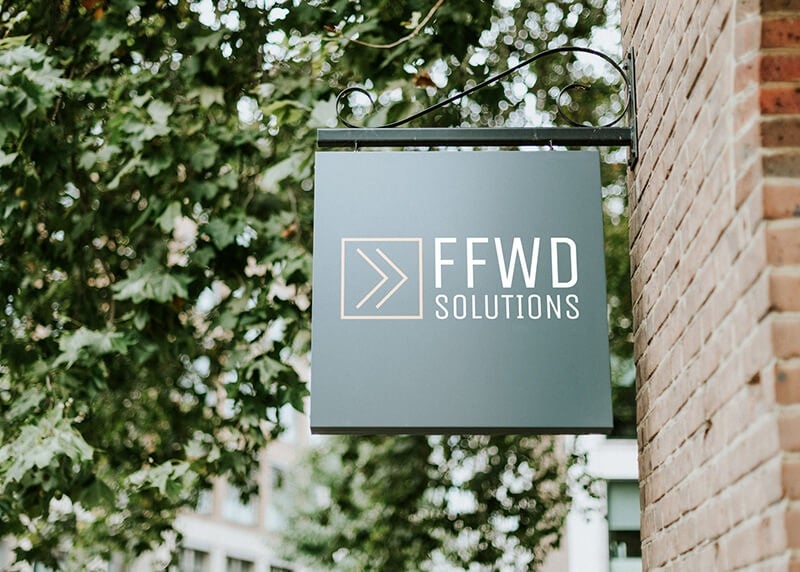 The company logo for FFWD Solutions printed on a green wall-mounted sign